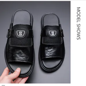 Détail de sandales en cuir noir pour hommes avec boucle métallique et décoration d'écusson S
