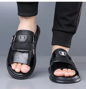 Vue rapprochée de sandales en cuir noir pour hommes avec logo bouclier et boucle latérale.