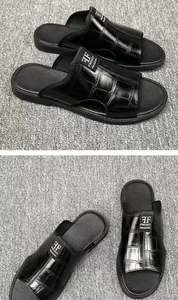 Close-up detail of men's black leather slippers featuring an embossed crocodile pattern