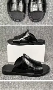 Detailed view of black crocodile texture men's sandals displayed on a minimalist white block