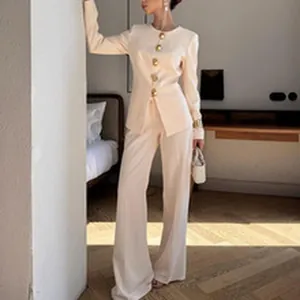 Elegante completo due pezzi crema con giacca sfiancata, bottoni dorati e pantaloni larghi.