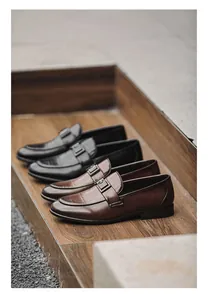 Detail of black and brown men's leather loafers with crocodile texture on wooden steps