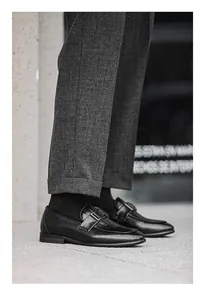 Detailed view of black leather loafers with metallic buckle and embossed texture