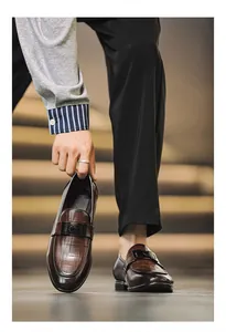Detail view of classic brown leather loafers for men featuring a stylish metal buckle.