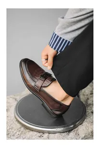 Elegant brown leather men's loafers with a classic metal buckle, close-up detail view.