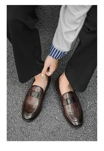 Top-down perspective of men's dark brown loafers with crocodile texture on asphalt pavement