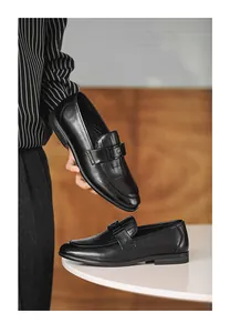 Close-up view of black leather loafers for men featuring an elegant metallic buckle design