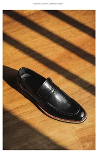 Detailed top-down view of premium black leather penny loafers on a sunlit wooden floor