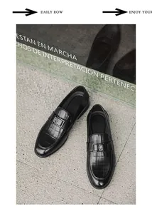 Detail view of black men's loafers with crocodile skin texture and heart spade buckle
