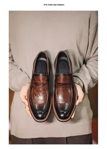 Detailed view of brown gradient leather loafers held by a person in a knit sweater