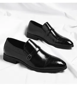 Detail view of men's black patent leather monk strap shoes with crocodile pattern.