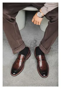 Macro view of brown leather penny loafers worn with casual brown trousers.