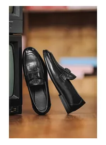 Detail view of black men's loafers featuring crocodile skin texture and buckle