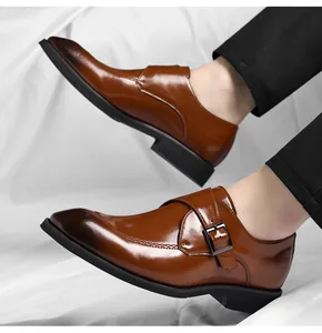 Dettaglio scarpe eleganti uomo in pelle marrone con cinturino a fibbia raffinato.