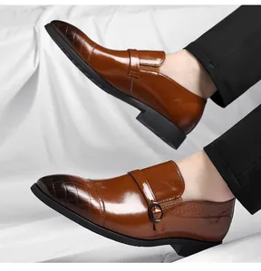 Detail of brown leather dress shoes with embossed crocodile texture and monk strap.