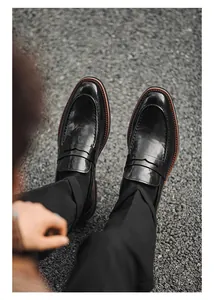 Top-down view of classic black leather penny loafers on a textured asphalt background