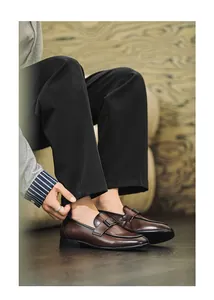 Close-up of men's brown leather loafers in British style worn with black trousers.