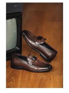 Close-up of brown leather loafers featuring black metal buckle details