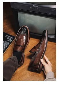 Close-up detail of brown gradient leather loafers with retro British style stitching.