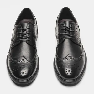 Top view detail of black leather brogue shoes showing intricate perforated wingtip patterns