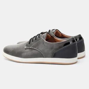 Dettaglio laterale di scarpe casual da uomo in pelle grigia con suola in gomma bianca