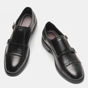 Detailed view of men's black leather double monk strap shoes with brogue pattern