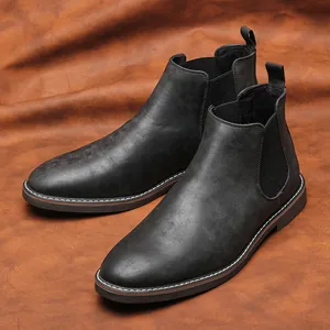 Primo piano di stivali Chelsea vintage da uomo in pelle nera consumata su sfondo marrone