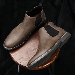 Stivaletti Chelsea vintage da uomo in pelle marrone con inserti elastici su uno sgabello.