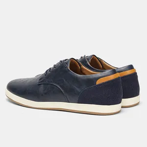 Vista detallada de zapatos casuales de hombre en cuero azul marino con talón de gamuza y suela blanca