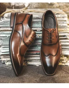 Nahaufnahme von braunen Oxford-Schuhen aus Leder vor einem Vintage-Zeitungs-Hintergrund