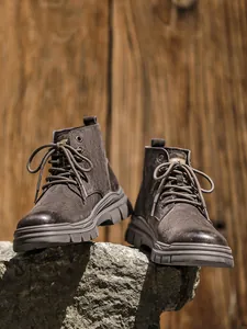 Detailed professional shot of brown suede high-top outdoor work boots on rugged rock