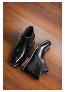 Close-up detail of stylish black leather Chelsea boots with side zipper on wooden floor