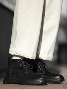 Detailed side view of black high-top outdoor work boots for men in street setting