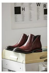 Close-up detail of men's stylish reddish-brown leather Chelsea boots with side zipper