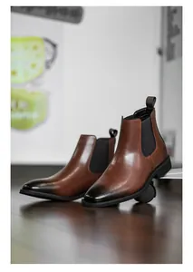 Retro bruin gepolijste leren Chelsea-laarzen voor heren op een stijlvolle houten vloer basis.