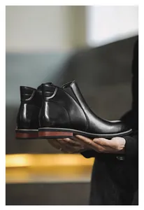 Side profile detail of black leather Chelsea boots showing sleek finish and wood grain sole