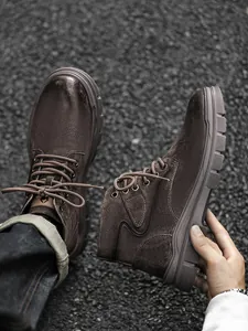 Detailed macro shot of brown leather Martin boots showing stitching and texture.