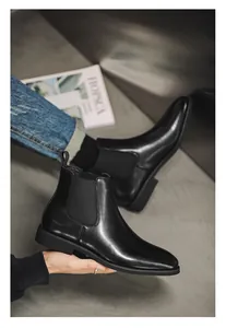Gedetailleerde weergave van gepolijste zwarte lederen Chelsea boots met elastische zijden.