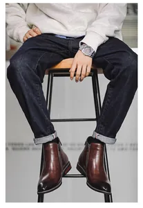 Close-up detail of stylish brown leather Chelsea boots with side zippers worn by model