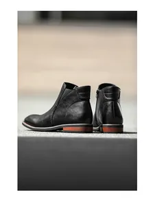 Rear view detail of black leather men's Chelsea boots with side zipper and stacked heel