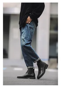 Gedetailleerd zijaanzicht van klassieke zwarte lederen Chelsea boots met jeans.