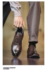 Κοντινή λήψη πολυτελών καφέ παπουτσιών Oxford brogue με κομψή παρουσίαση στο χέρι
