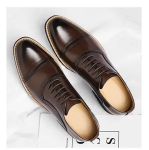 Top view detail of brown leather cap-toe business shoes on white fabric background