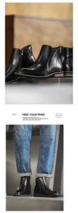 Detail view of black leather men's Chelsea boots with side zippers and square toe.