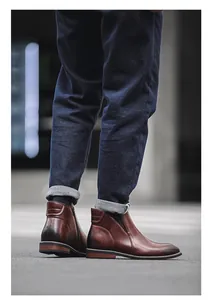 Close-up of men's brown leather Chelsea boots with side zippers on urban street.