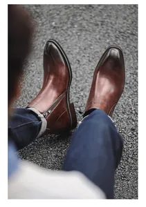 Detailed top view of men's brown leather Chelsea boots with side zipper on asphalt