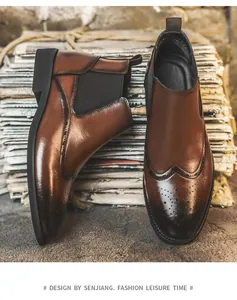 Detailansicht brauner Brogue Chelsea-Stiefel mit Flügelkappen-Schnitzerei vor Vintage-Hintergrund