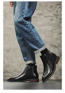Detailed side view of black men's leather Chelsea boots with functional side zippers