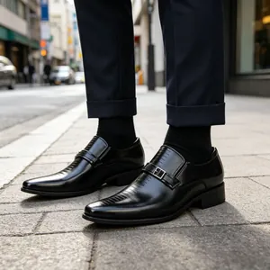 Close-up of men's black leather business loafers with buckle and textured vamp in street setting