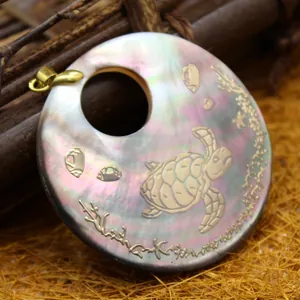 Iridescent shell pendant featuring a sea turtle engraving and golden ocean motifs